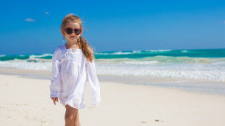 Adorable little girl relaxing and have fun at tropical white beach