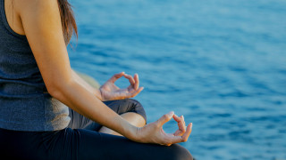 The woman meditating in a yoga pose on the tropical beach. Female meditating overlooking the beautiful sunrise. Healthy mind body and spirit concept.