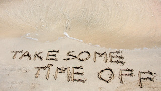 TAKE SOME TIME OFF written on sand on a beautiful beach blue waves in background